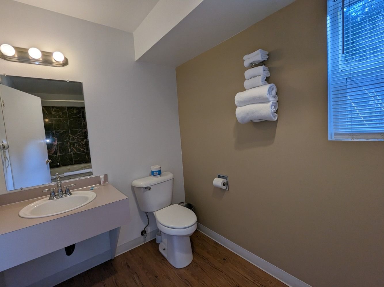 A bathroom with a toilet , sink and mirror.