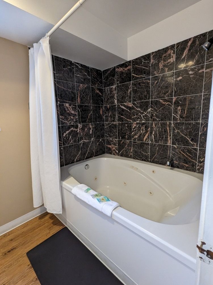 A bathroom with a jacuzzi tub and a shower curtain.