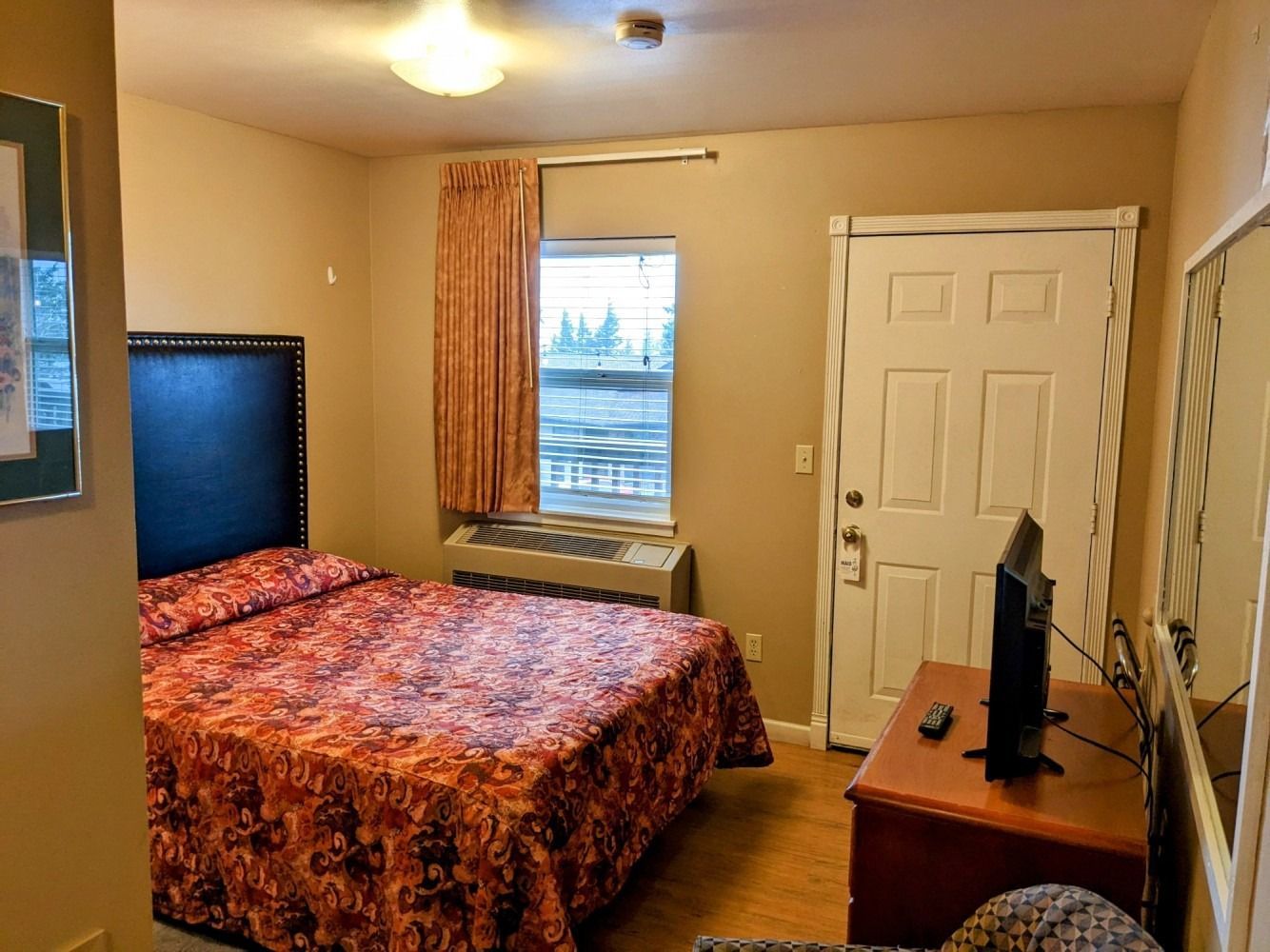 A hotel room with a bed and a television