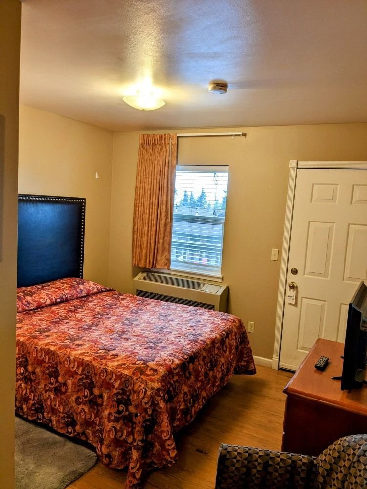 A hotel room with a bed and a television