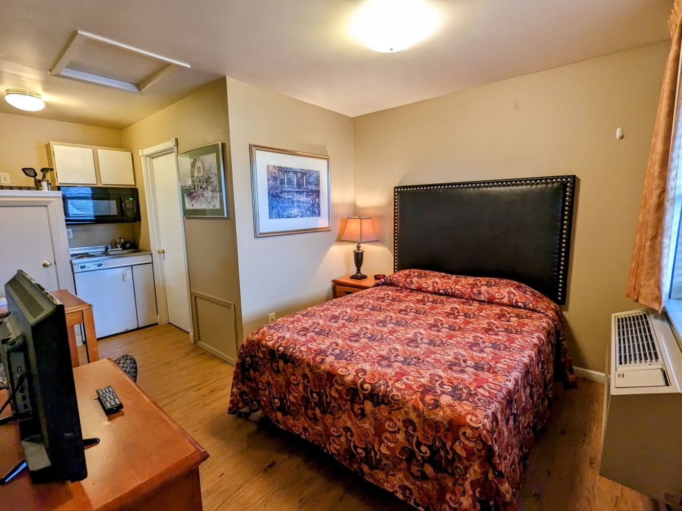 A hotel room with a king size bed and a flat screen tv