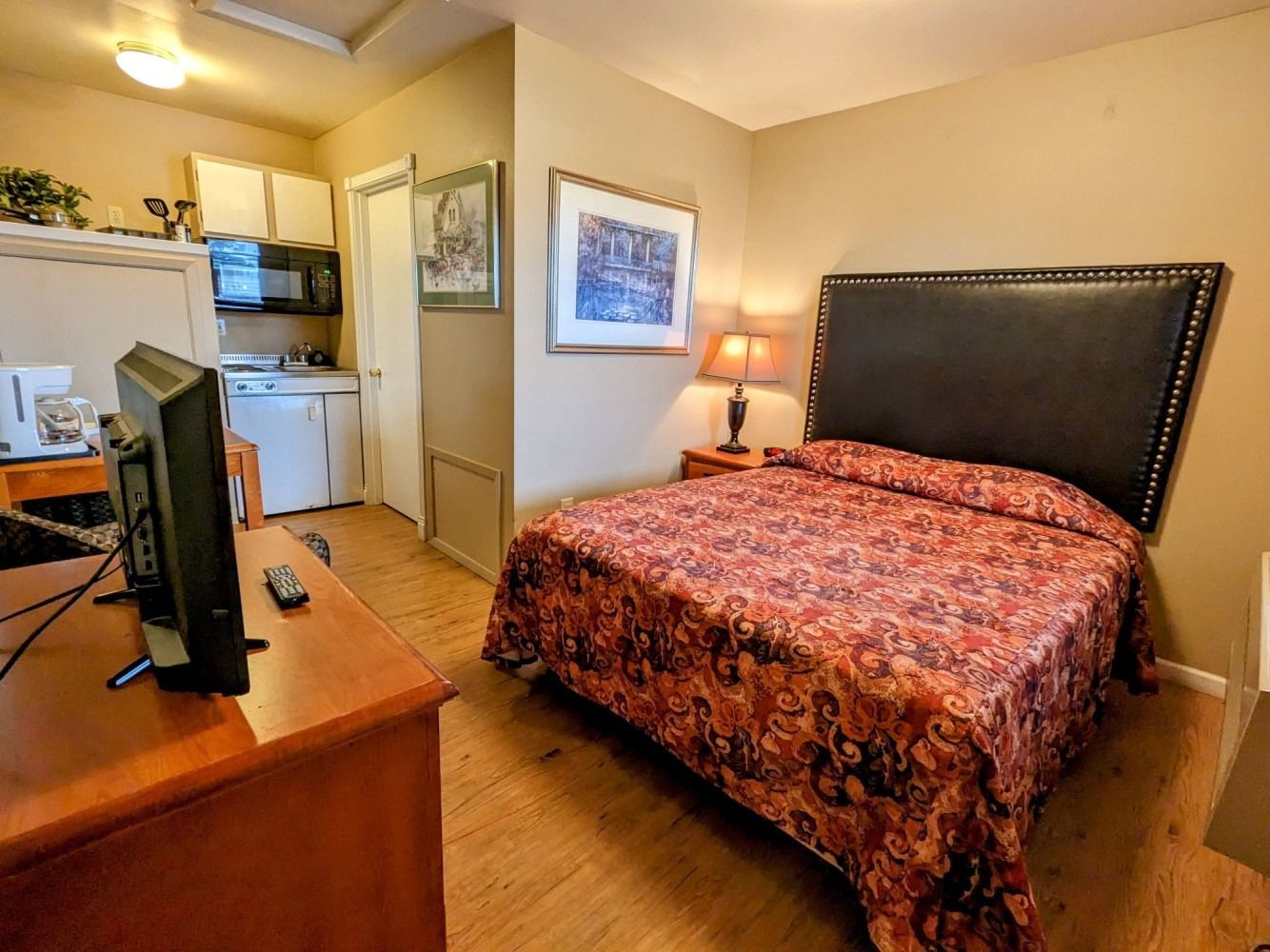 A hotel room with a king size bed and a flat screen tv