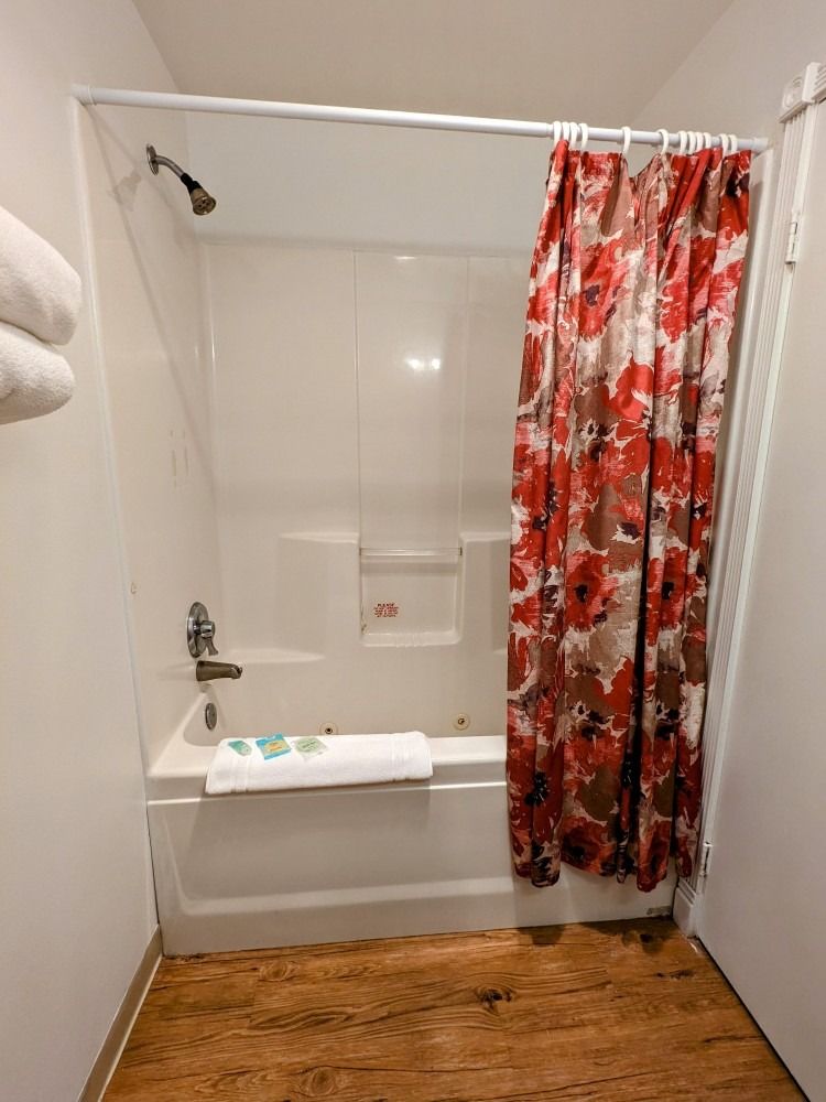 A bathroom with a bathtub and shower with a red shower curtain