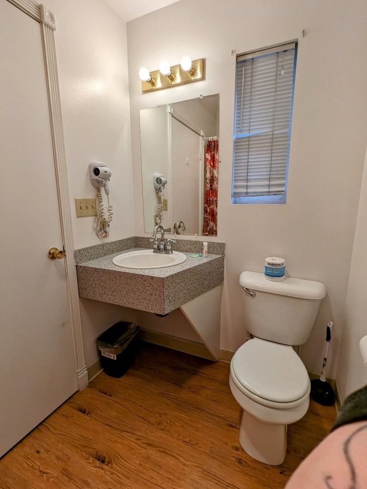 A bathroom with a toilet , sink and mirror