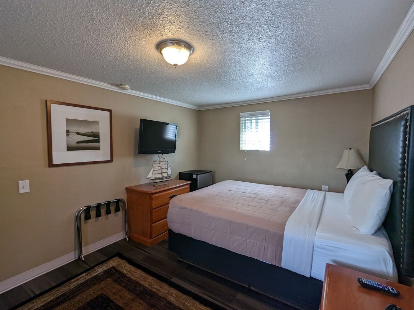 A hotel room with a king size bed and a flat screen tv.