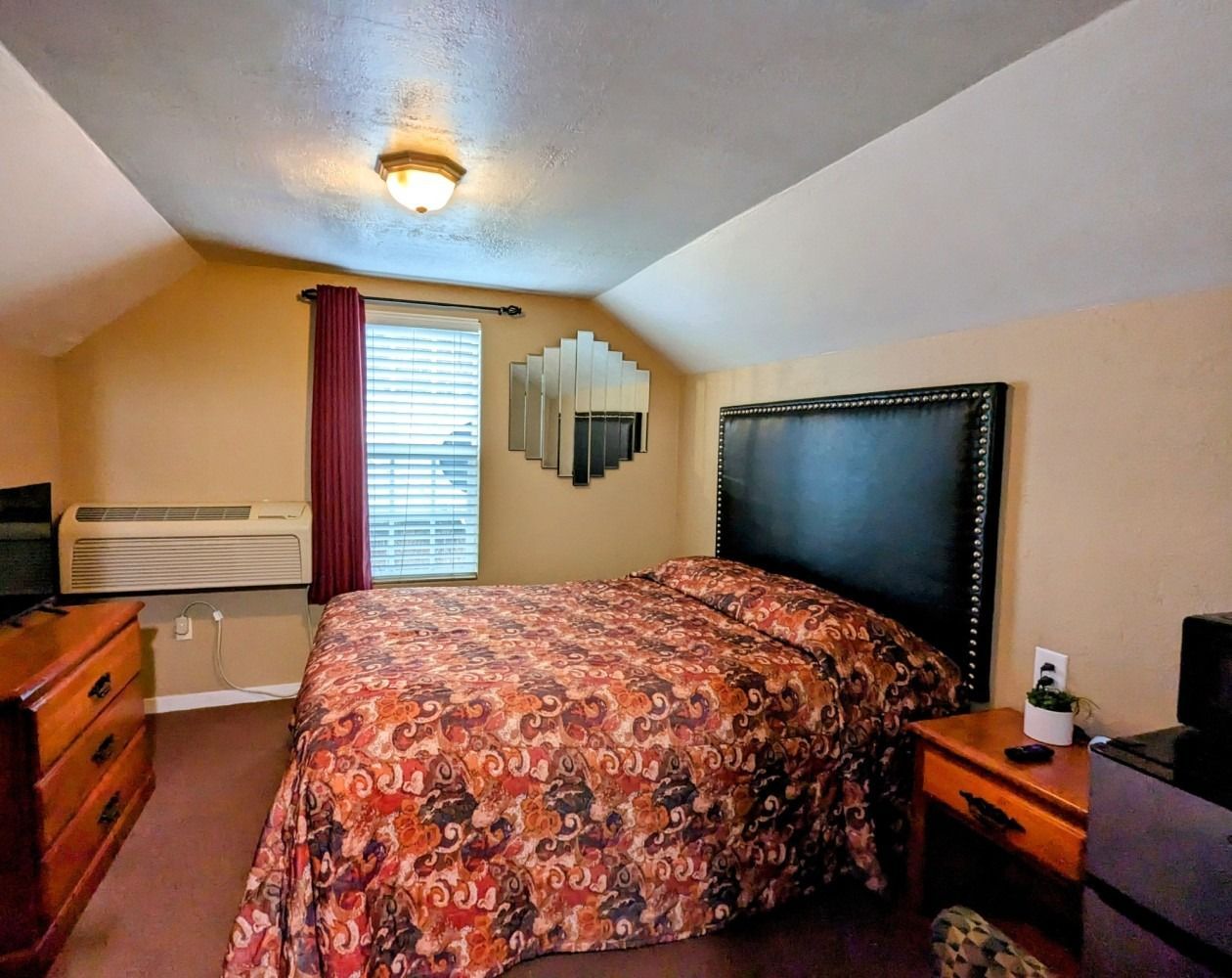 A hotel room with a large bed and a mirror on the wall