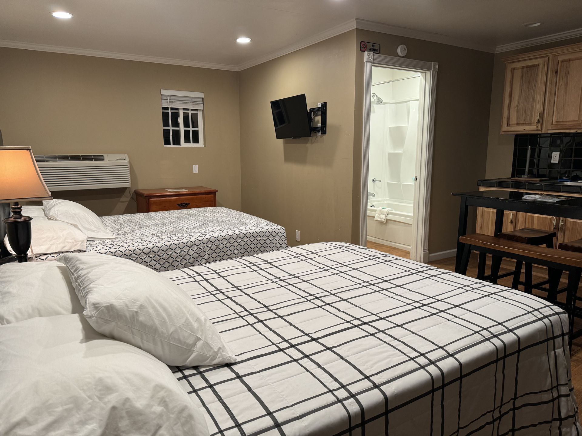 A hotel room with two beds and a television on the wall.