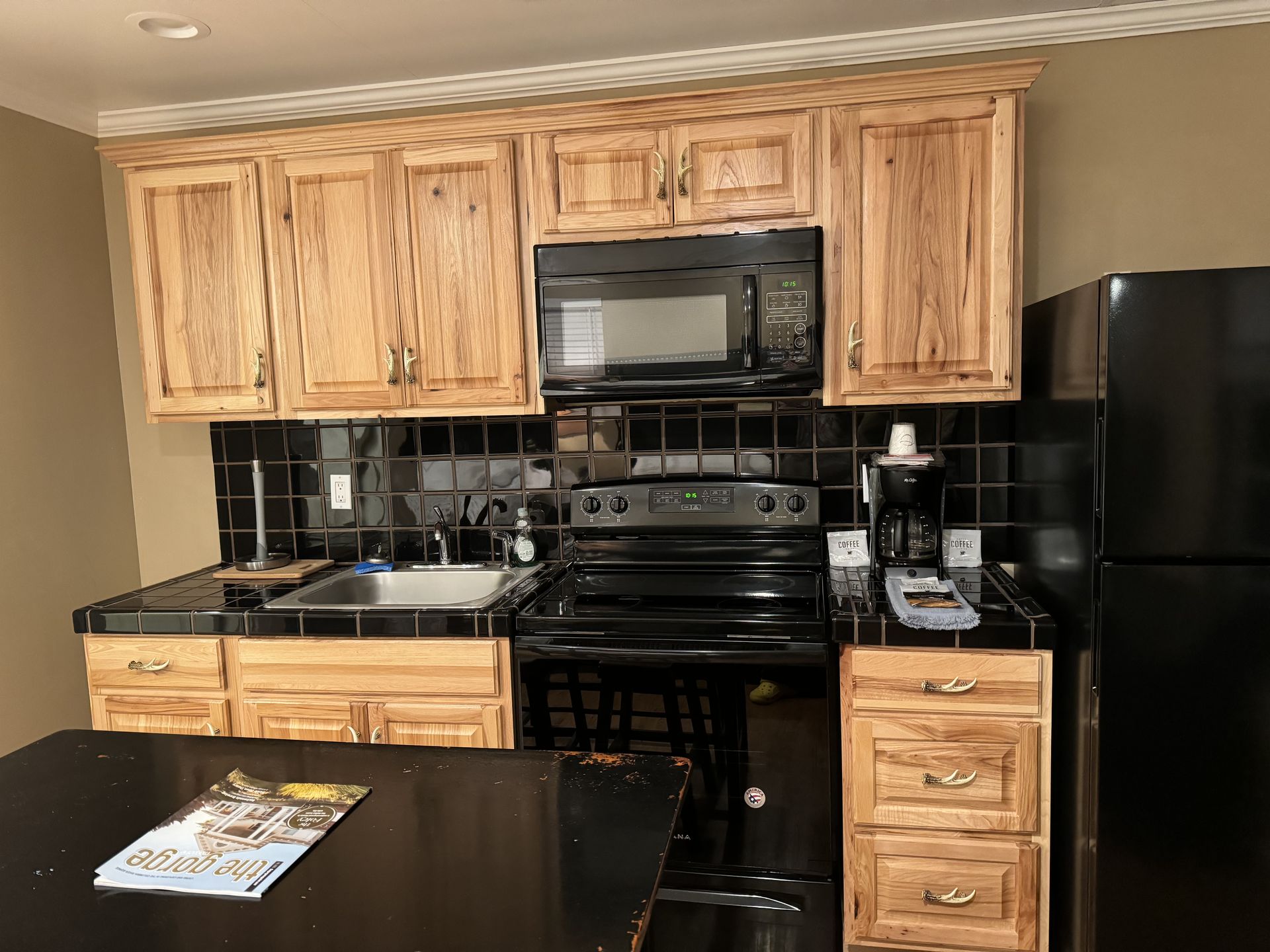 A kitchen with wooden cabinets and a black refrigerator