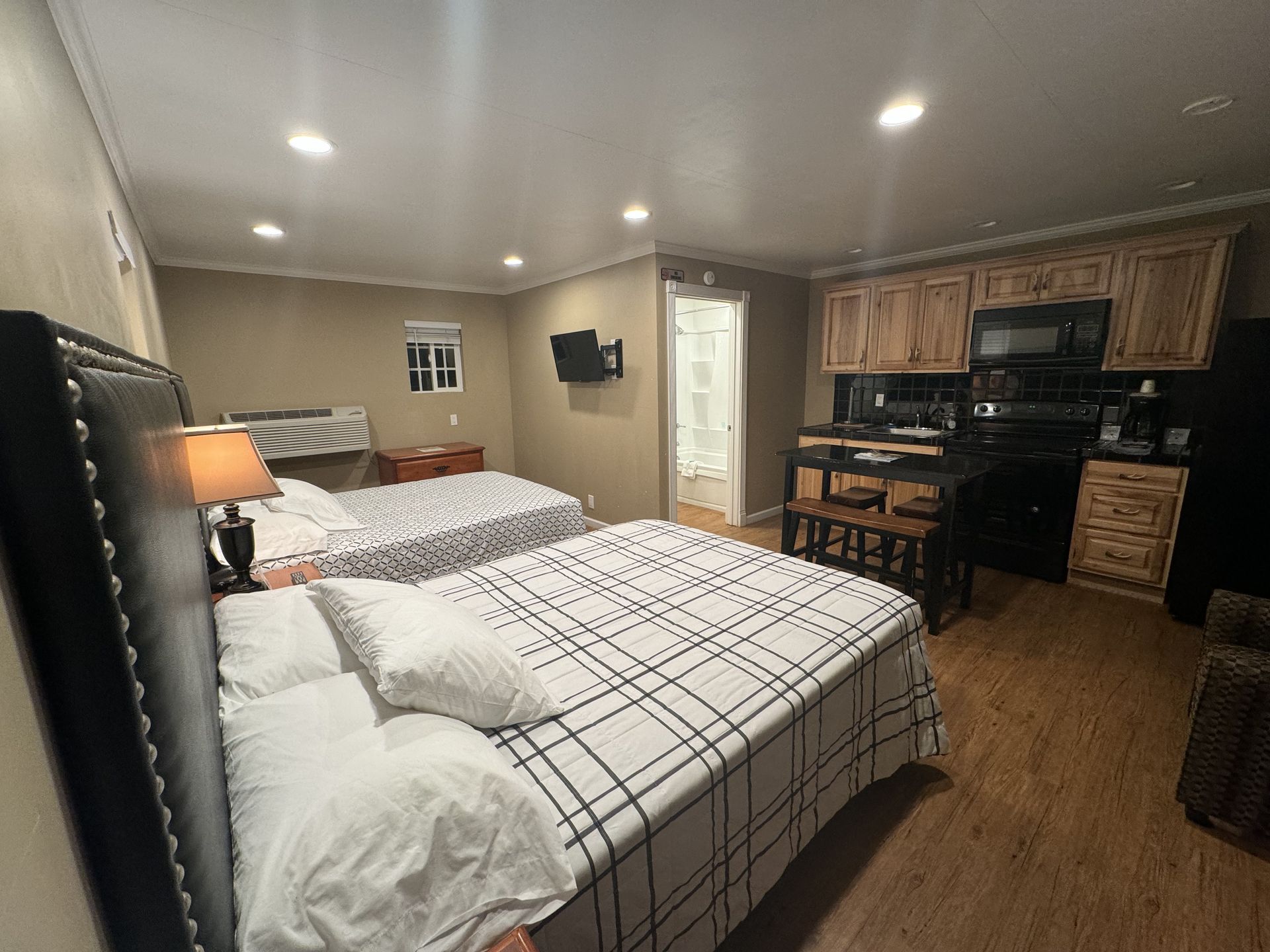 A bedroom with two beds , a kitchen , and a television.