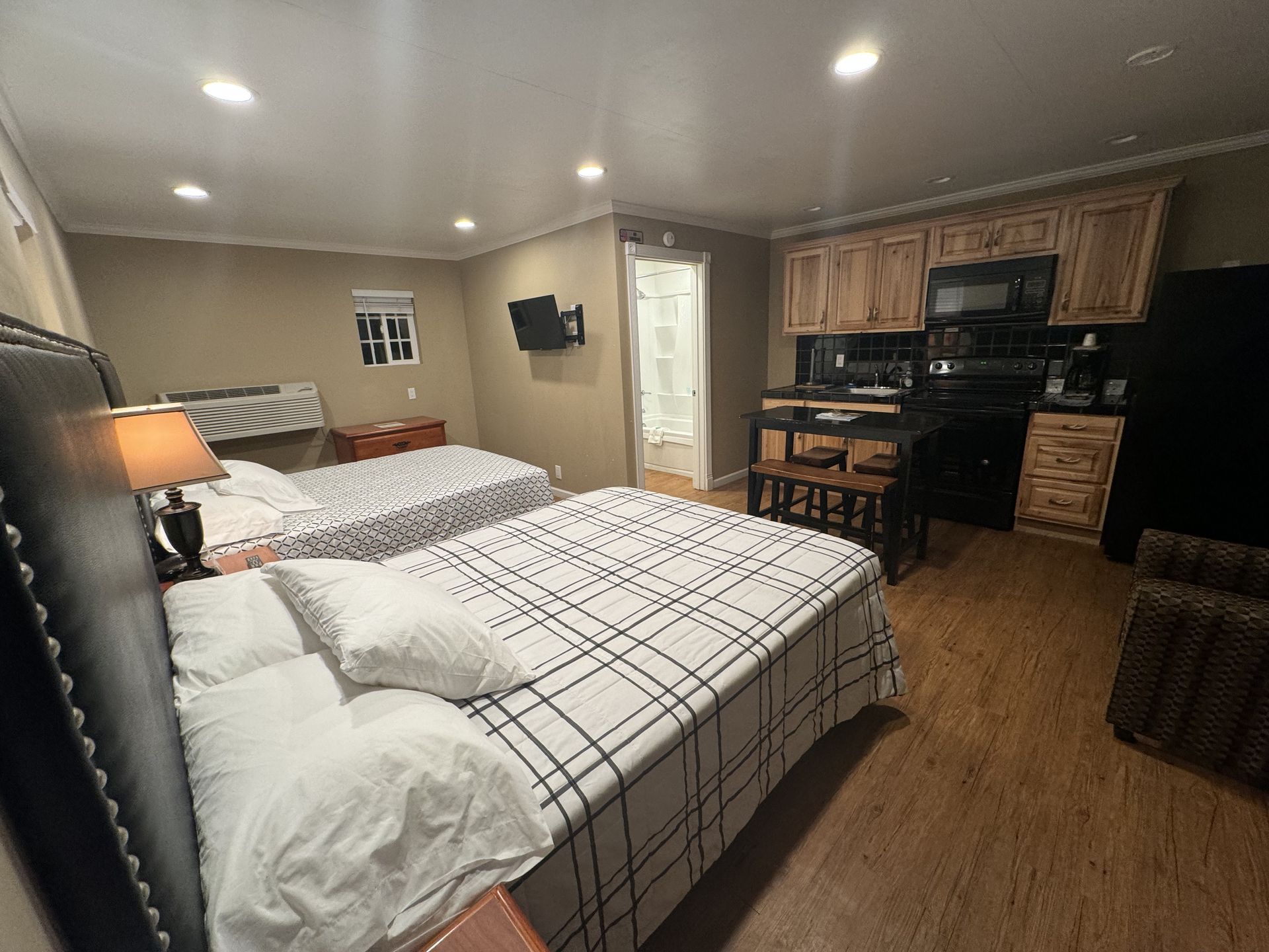 A hotel room with two beds and a kitchen.