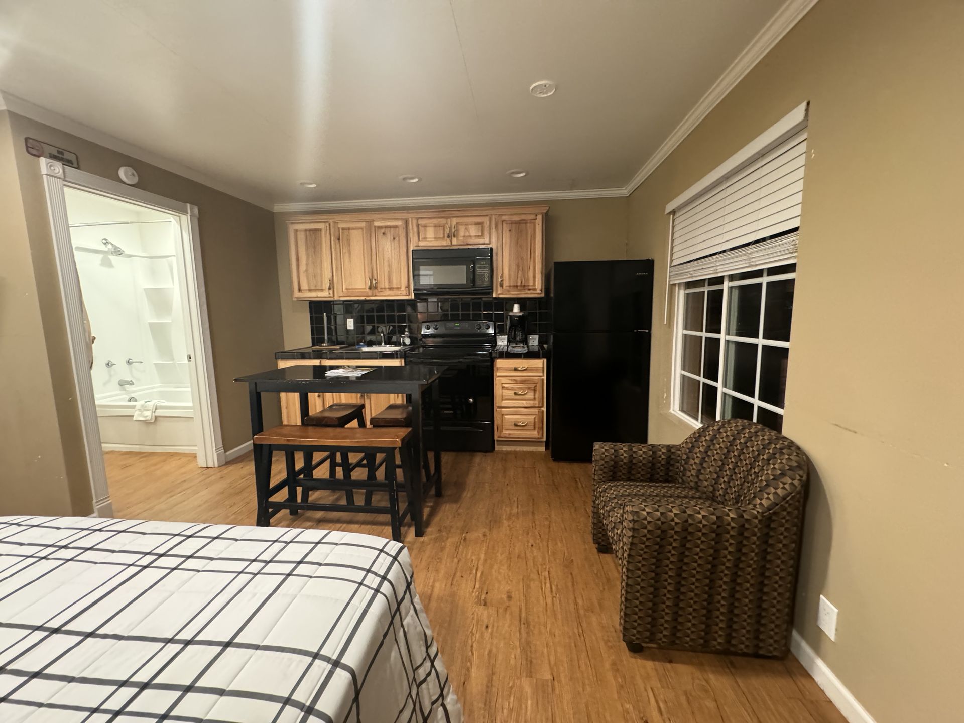 A bedroom with a bed , chair , table and kitchen.
