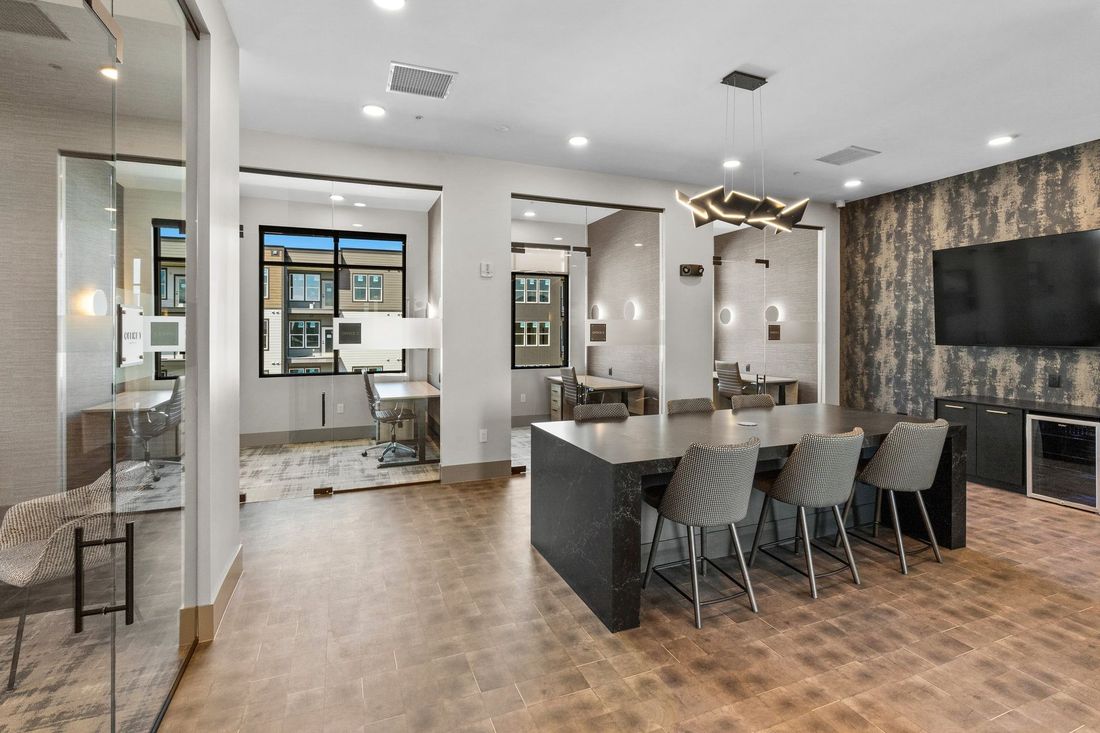 Modern office space with a large island, chairs, and multiple work areas.