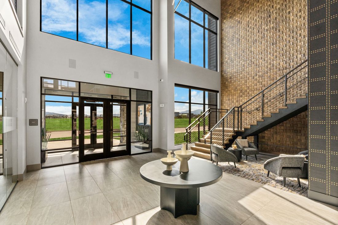 Modern lobby with a table, staircase, and large windows with a view.