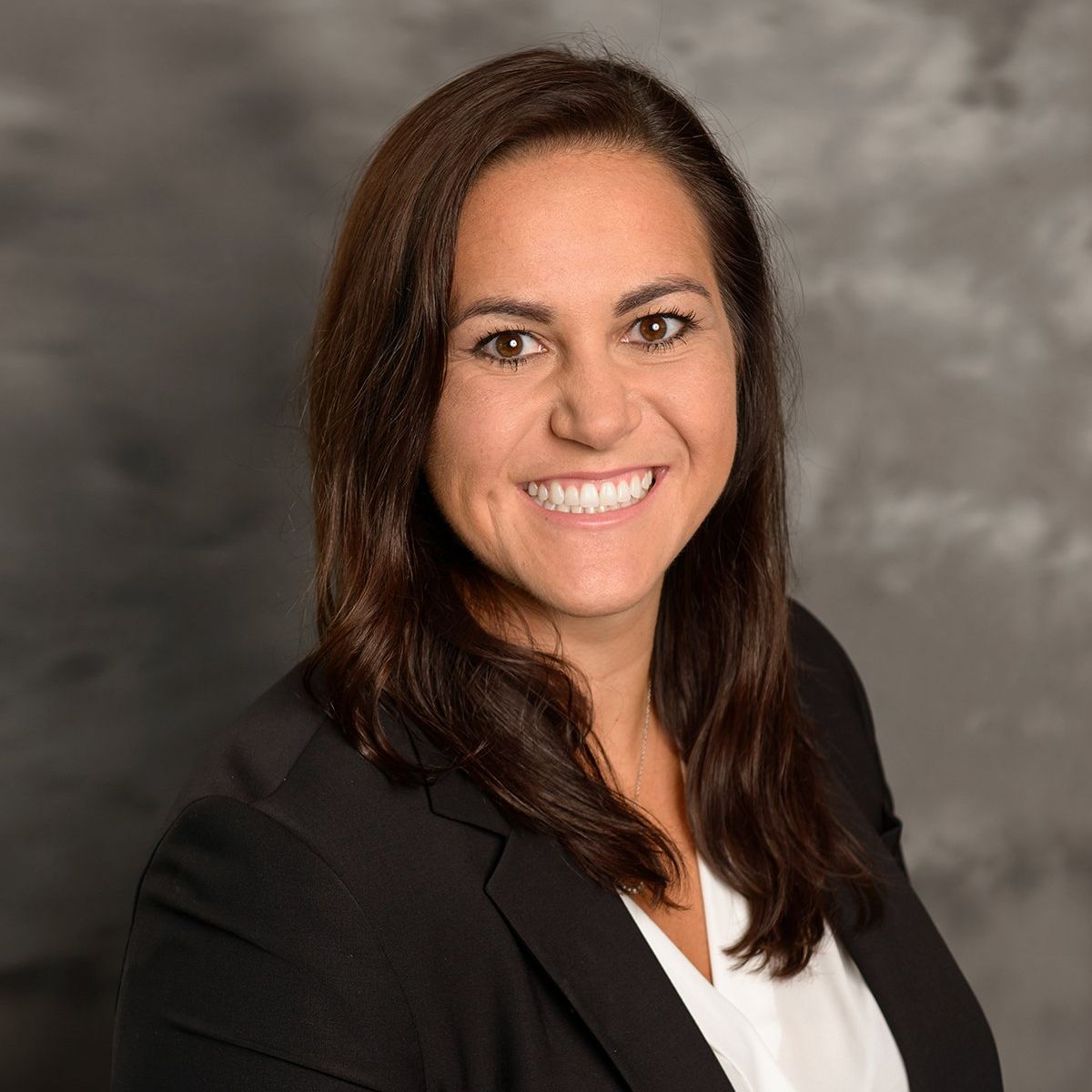 A woman in a black jacket and white shirt is smiling for the camera.