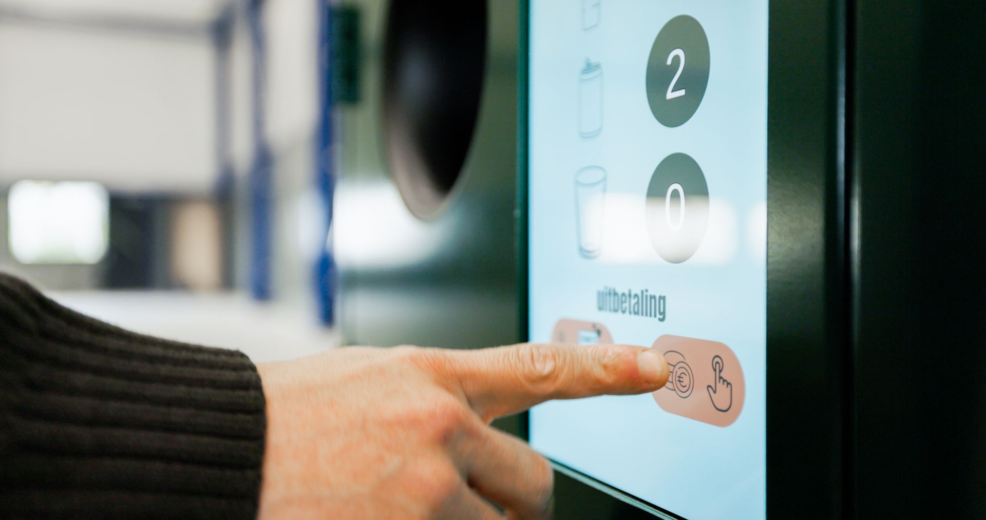 Hand pressing a touchscreen reverse vending machine button with numbered selection icons