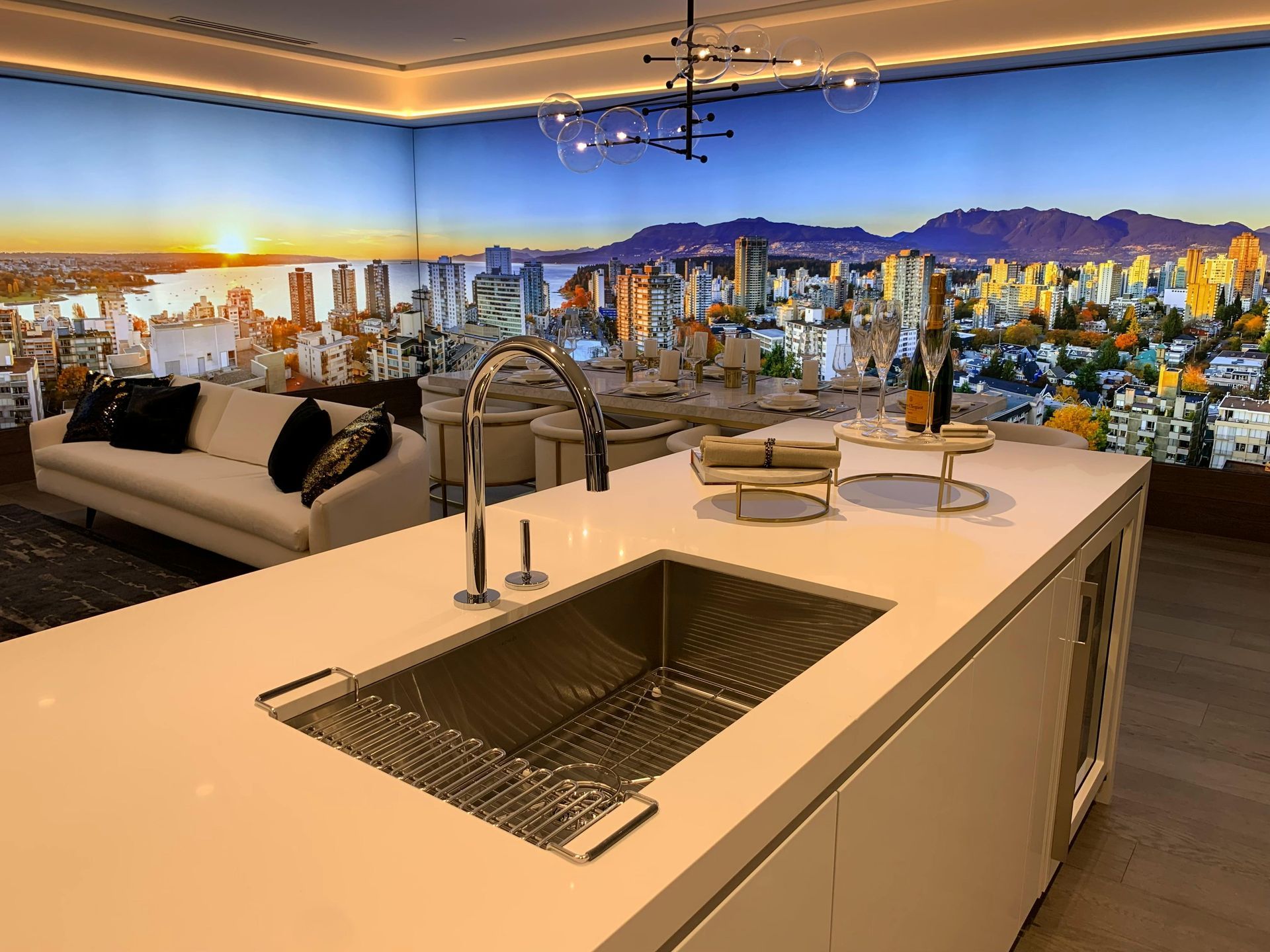 Modern kitchen with white island, stainless steel sink, cityscape mural background, sofa.