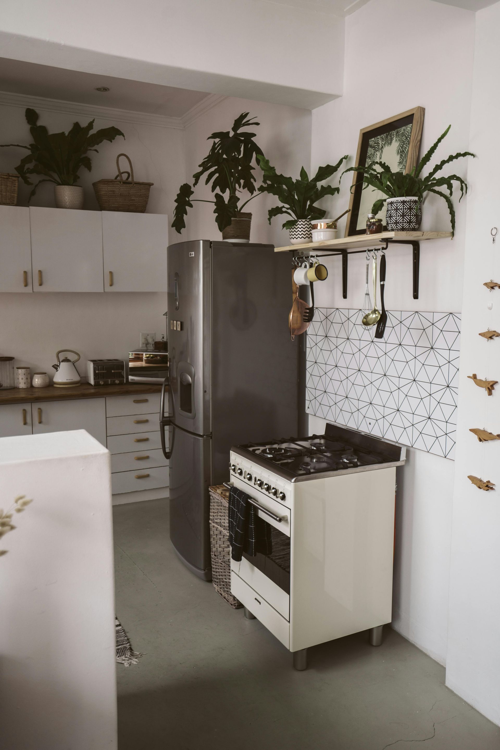Kitchen with stainless steel refrigerator, white stove, plants, shelves, and cabinets.
