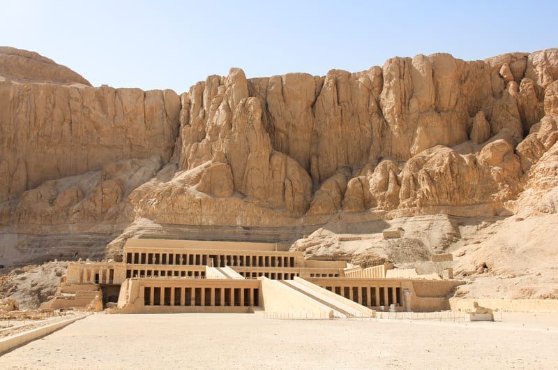 Temple of Hatshepsut in Egypt, a colonnaded structure in desert, against a tan cliff.