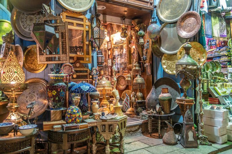 Shop display filled with ornate brass and copper items in a Middle Eastern market.