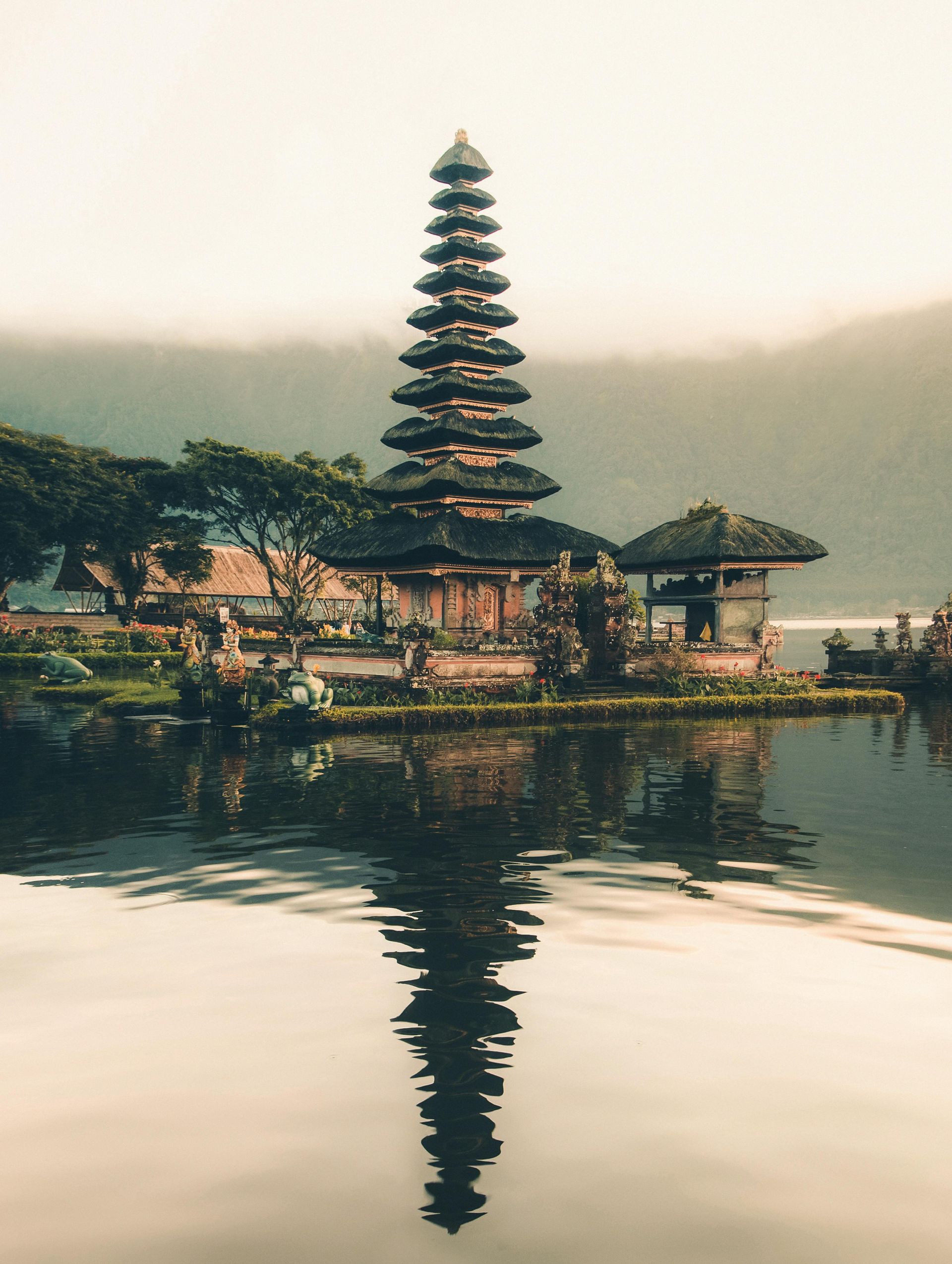 Temple and its reflection in a calm lake, with hills in the background.