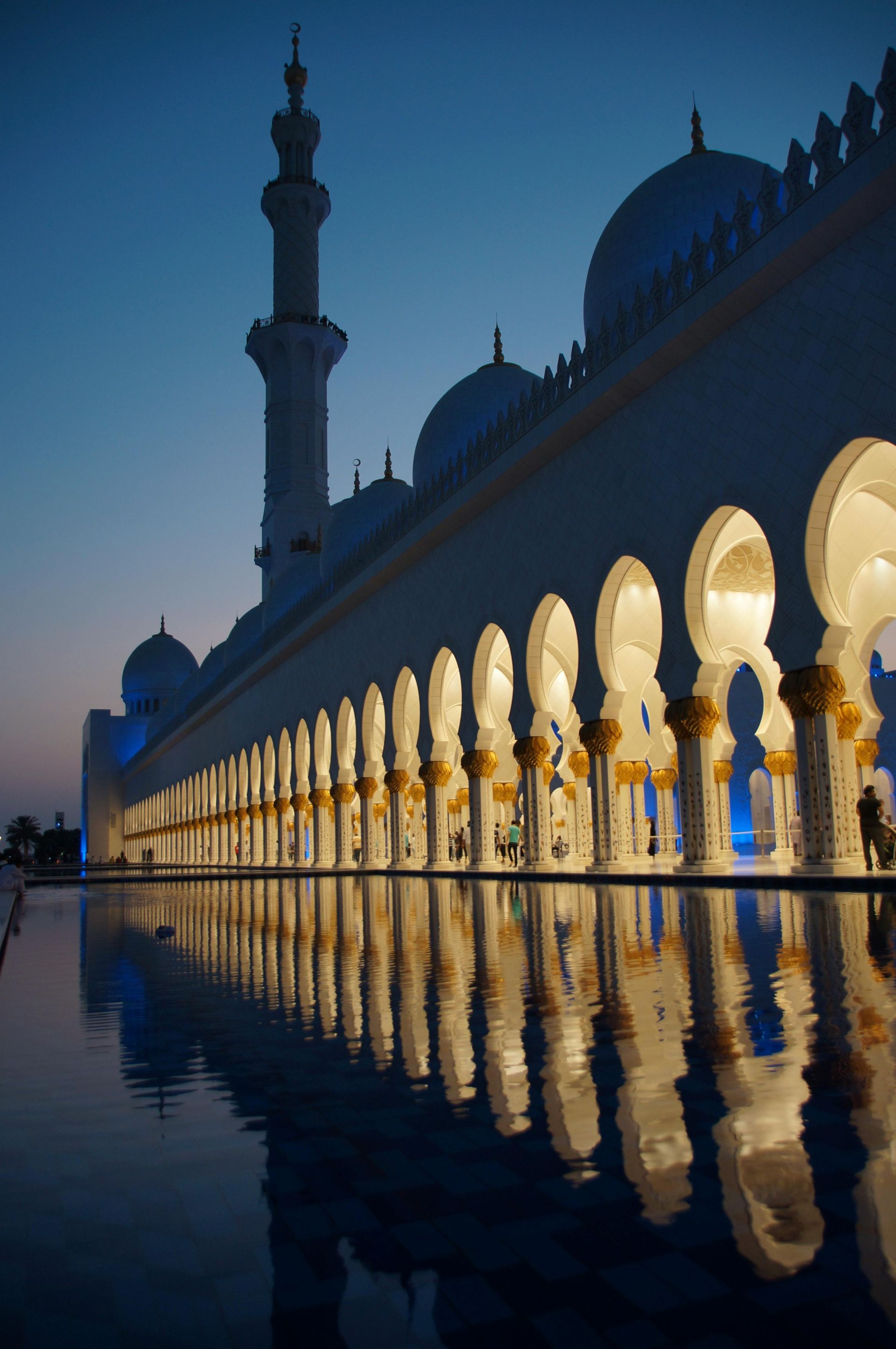 Sheikh Zayed Grand Mosque reflects in water at dusk.