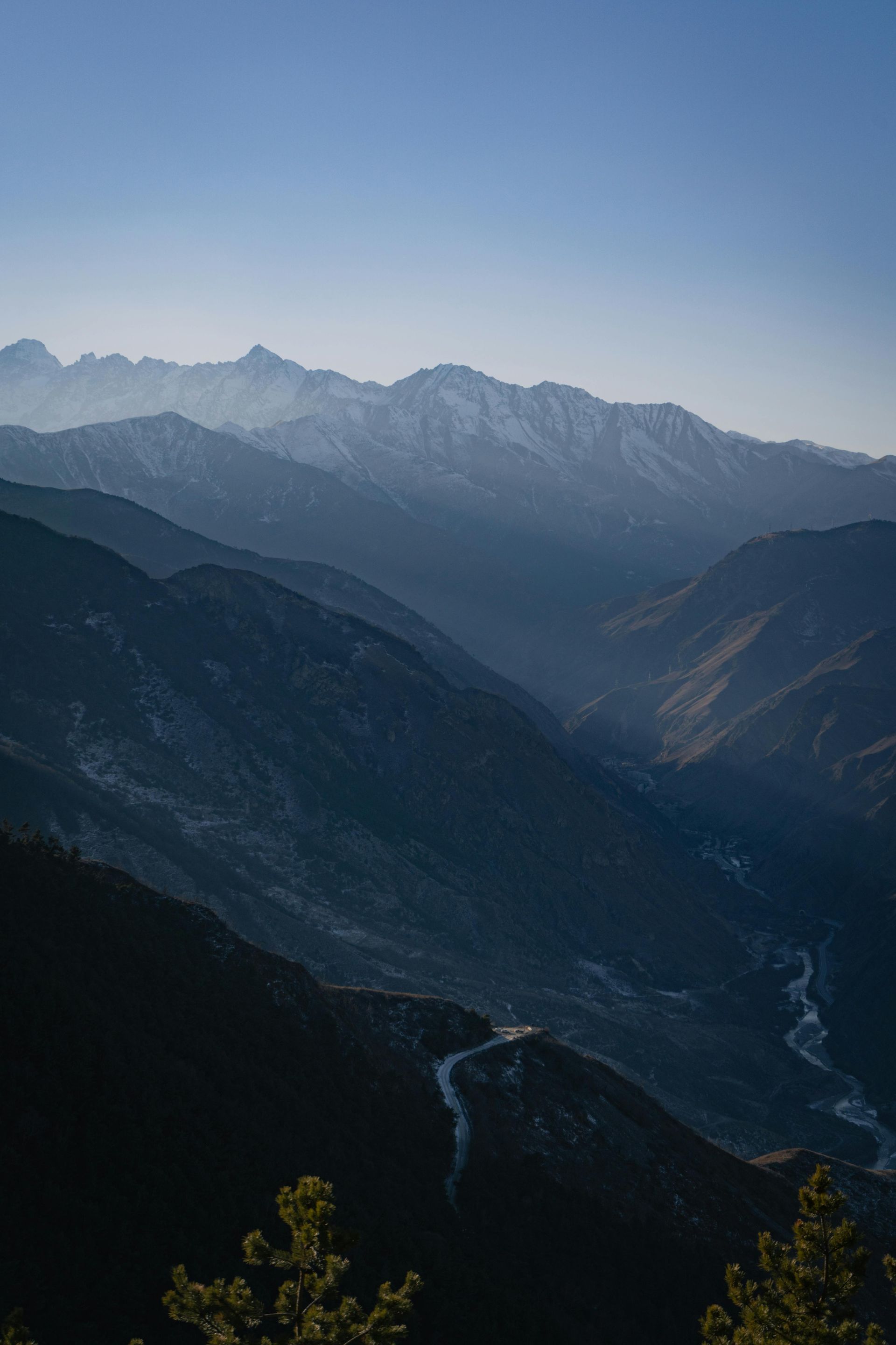 Mountains shrouded in a blue haze with a winding road.