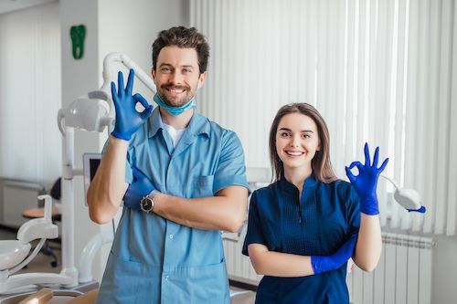 Dentist and assistant smiling, giving