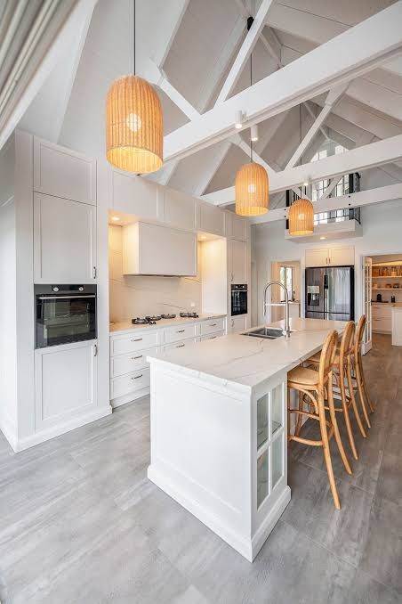 Bright white modern kitchen with island, bar stools, and warm pendant lights
