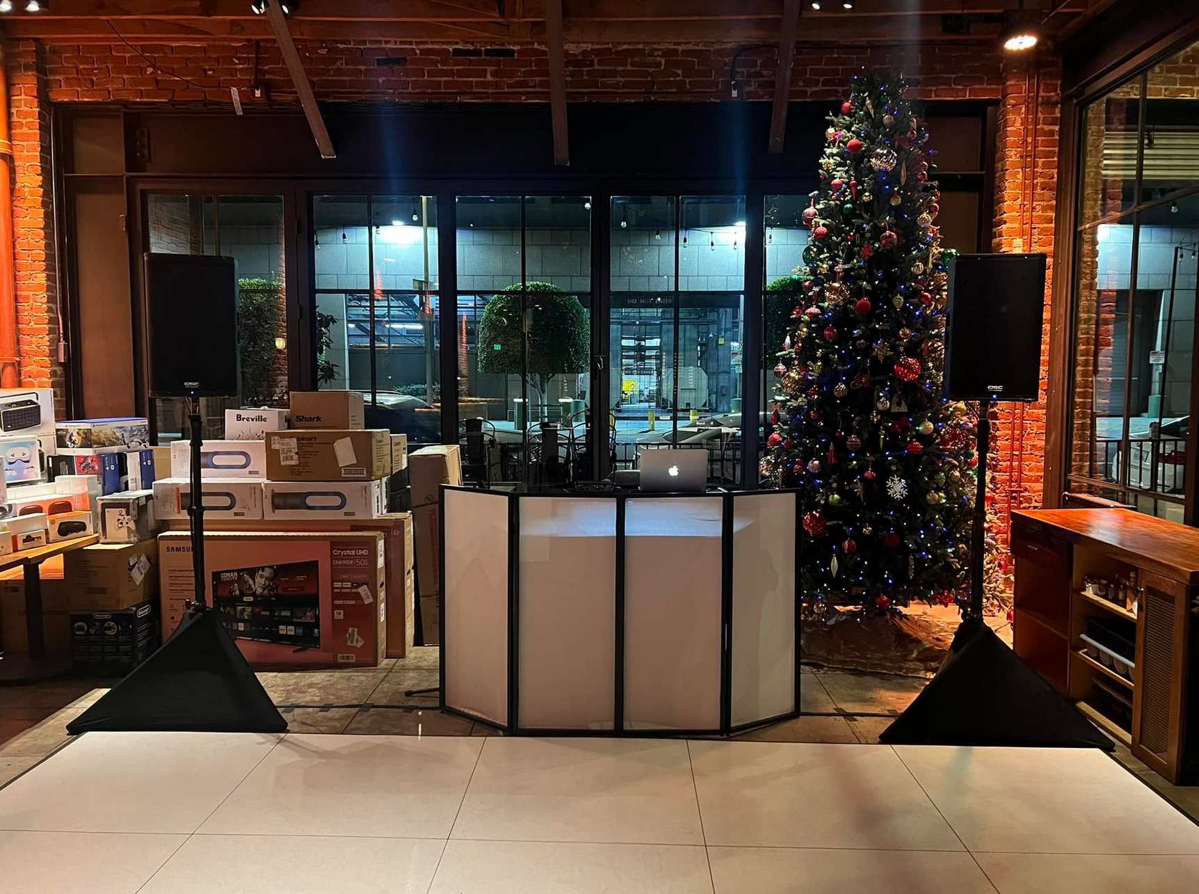 DJ setup with speakers, dance floor, and Christmas tree in a shop window.