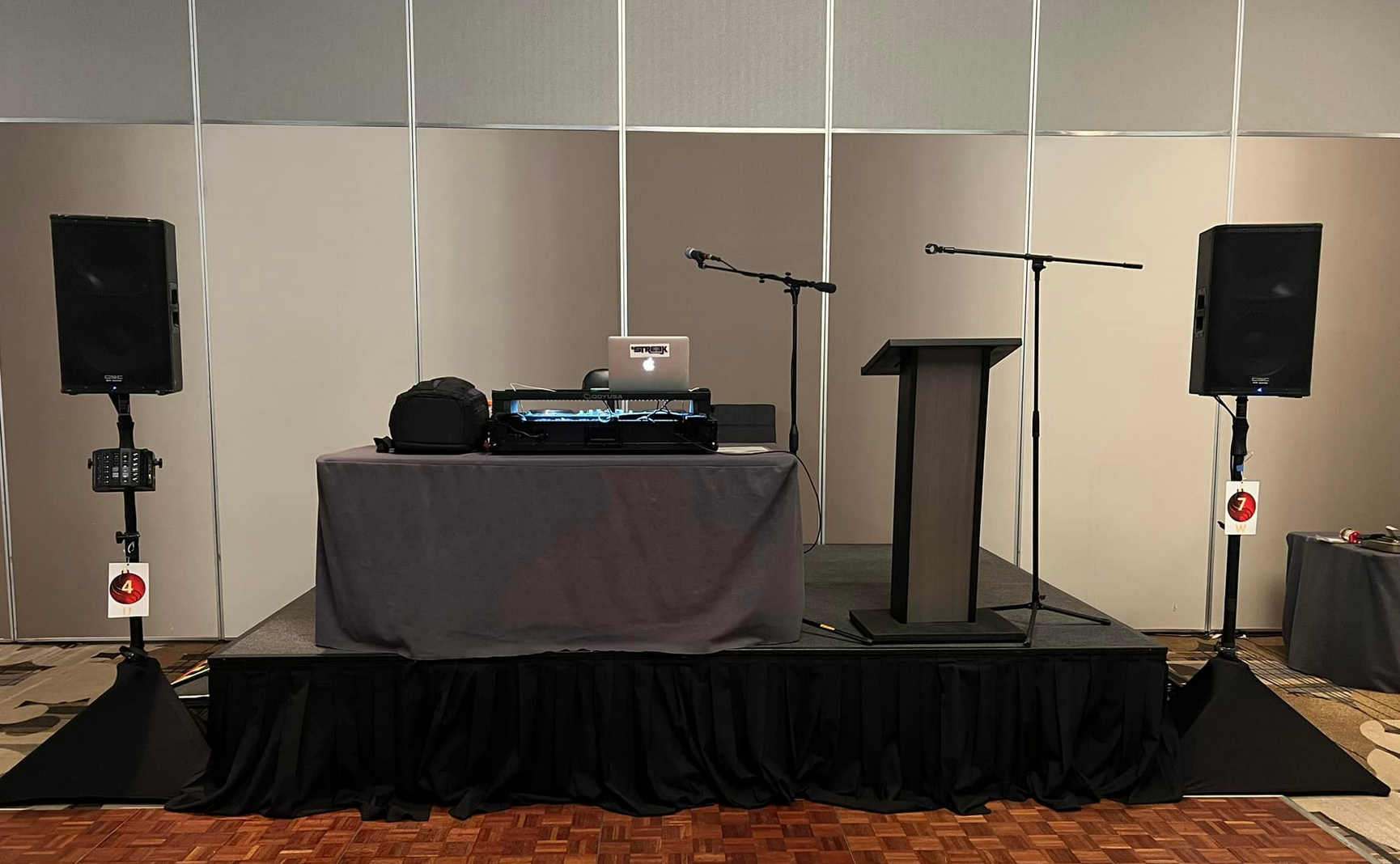 A stage setup with speakers, microphones, a soundboard, and a podium in a room.