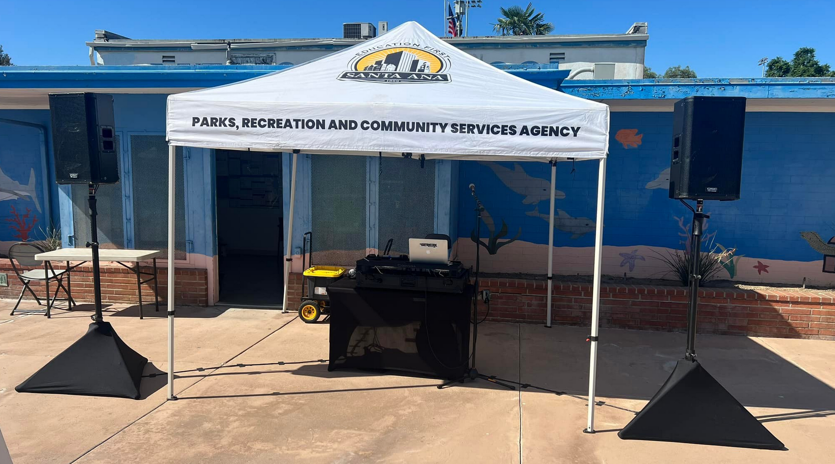White canopy with sound equipment, set up outdoors.