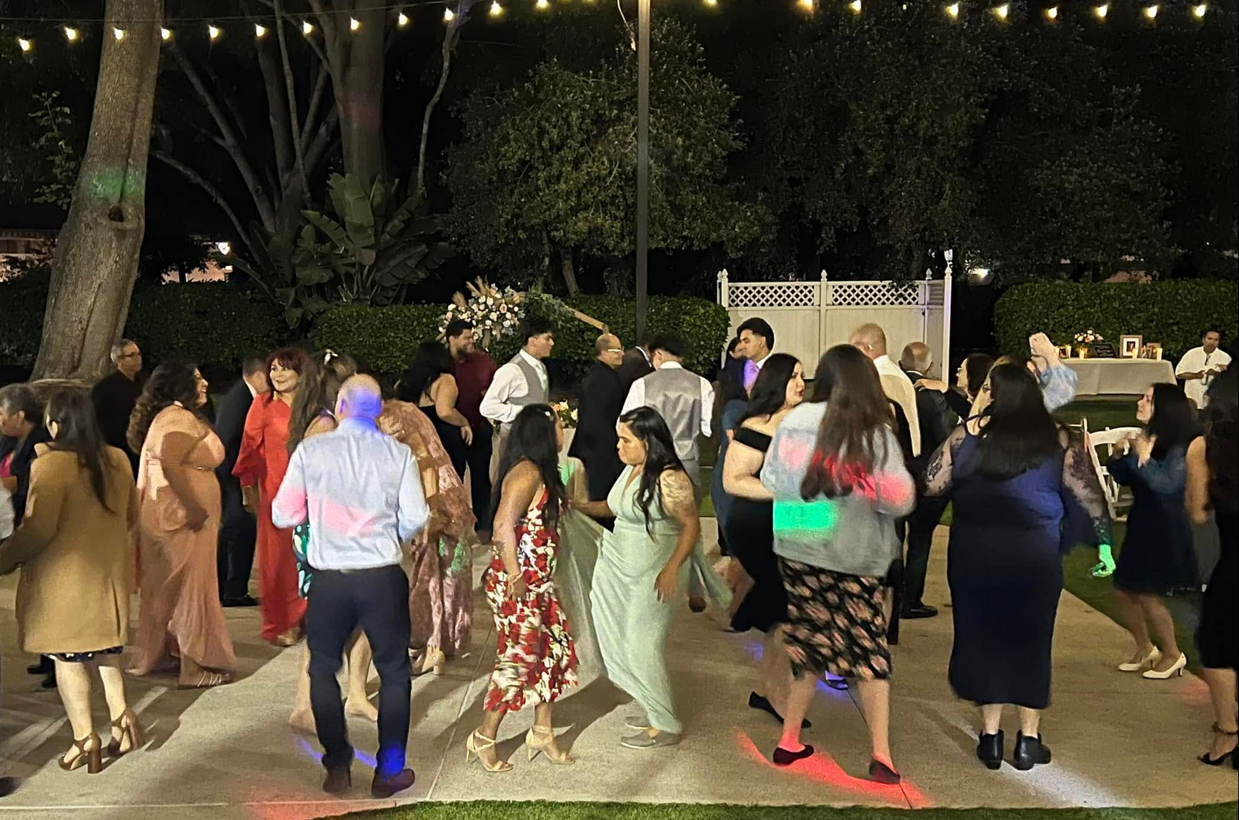 People dancing outdoors at night, string lights overhead.