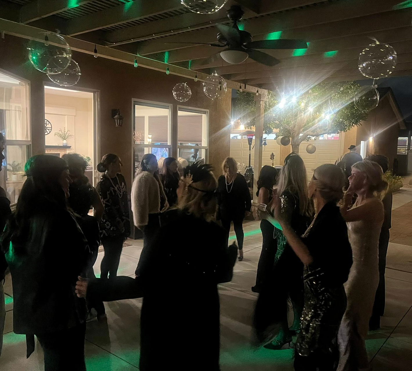 People dancing at a party outdoors at night, with disco balls and green lights.