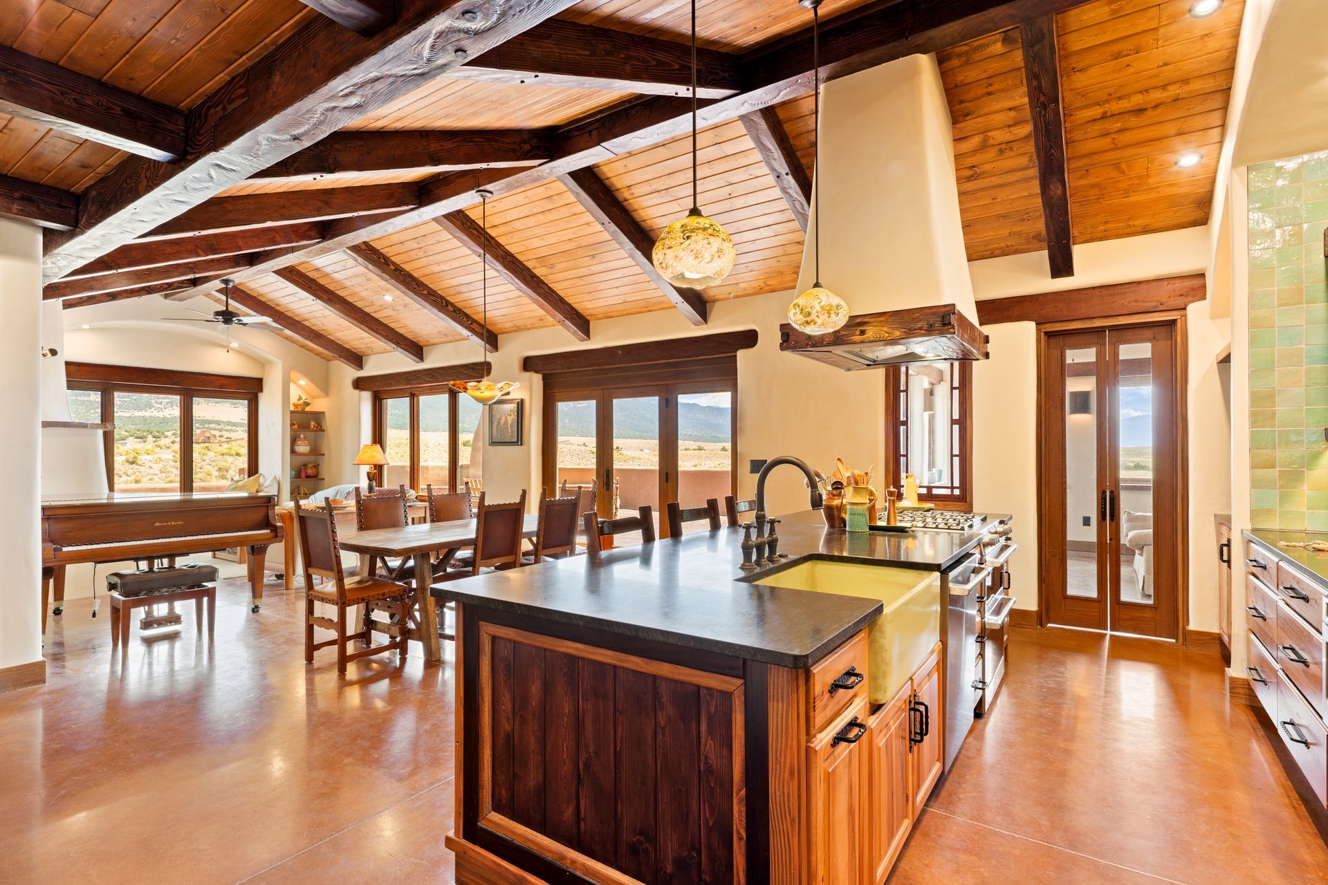 Bright open kitchen and dining area with wood beams, island, and large windows