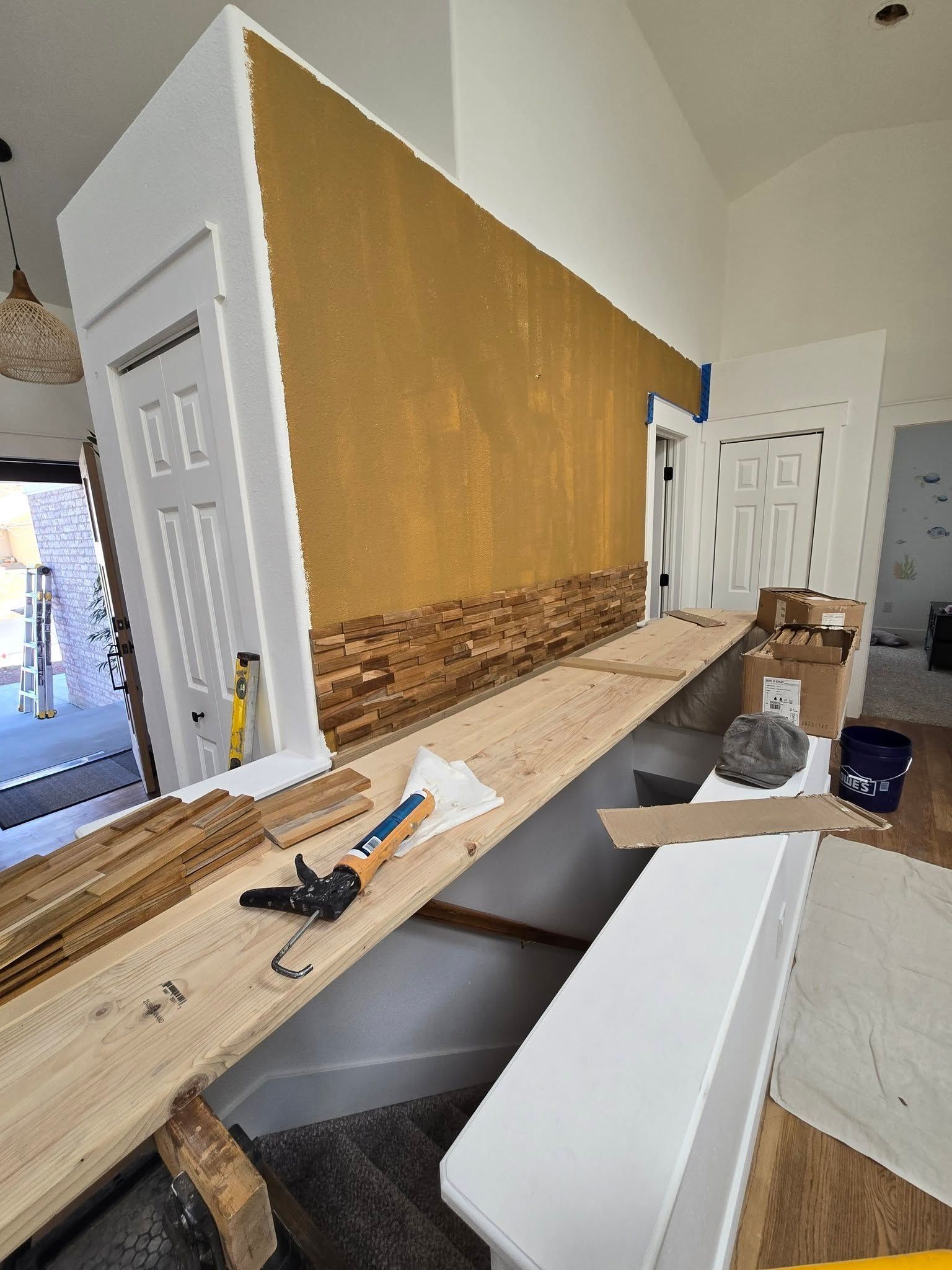 Renovated hallway with a built-in counter, tools, and drywall leaning against a gold accent wall