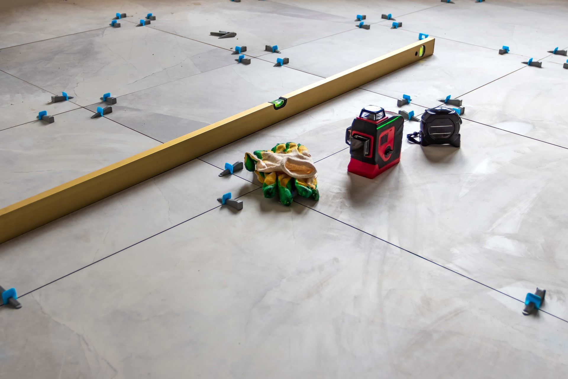 Small toy robots on a white floor with scattered blue pieces and a long wooden barrier