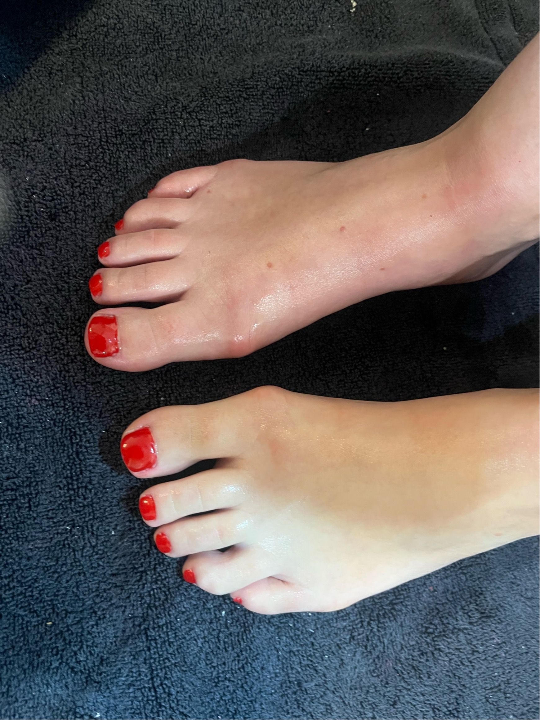 Manicured hands with long nude-pink nails resting on a white textured surface