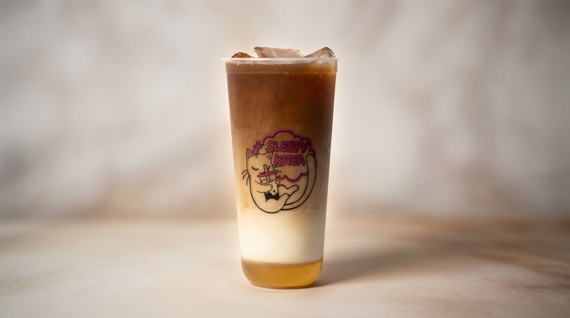 Iced layered coffee in a clear cup with a logo, on a light background