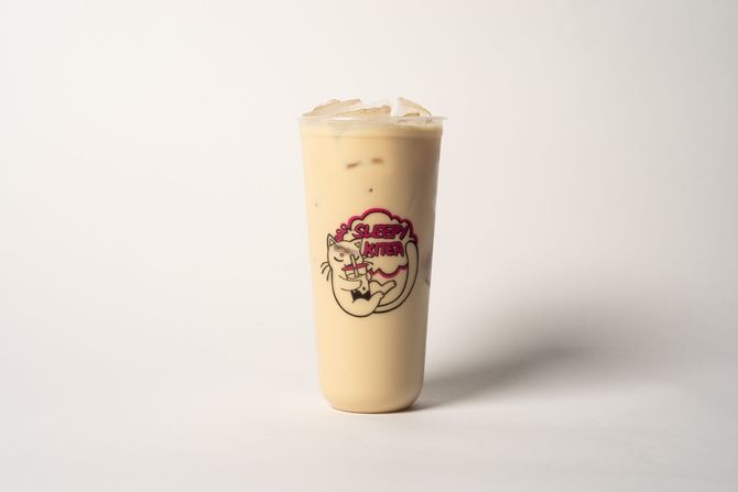 Tall iced milkshake topped with whipped cream and caramel drizzle on a pastel background