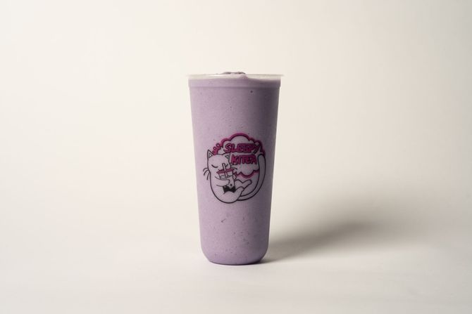 Tall iced milkshake topped with whipped cream and caramel drizzle on a pastel background