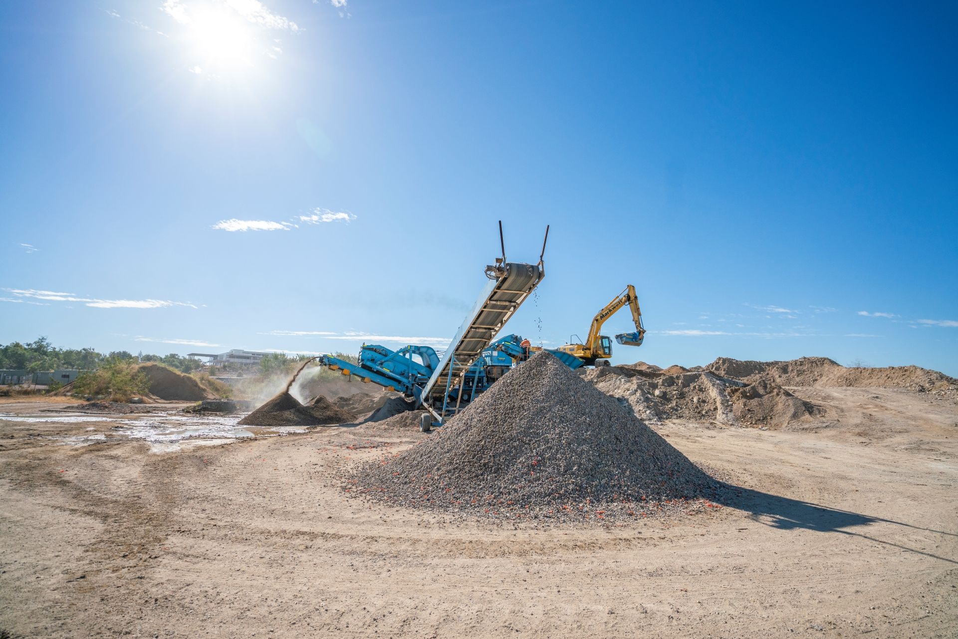 A pile of gravel is sitting in the middle of a dirt field.