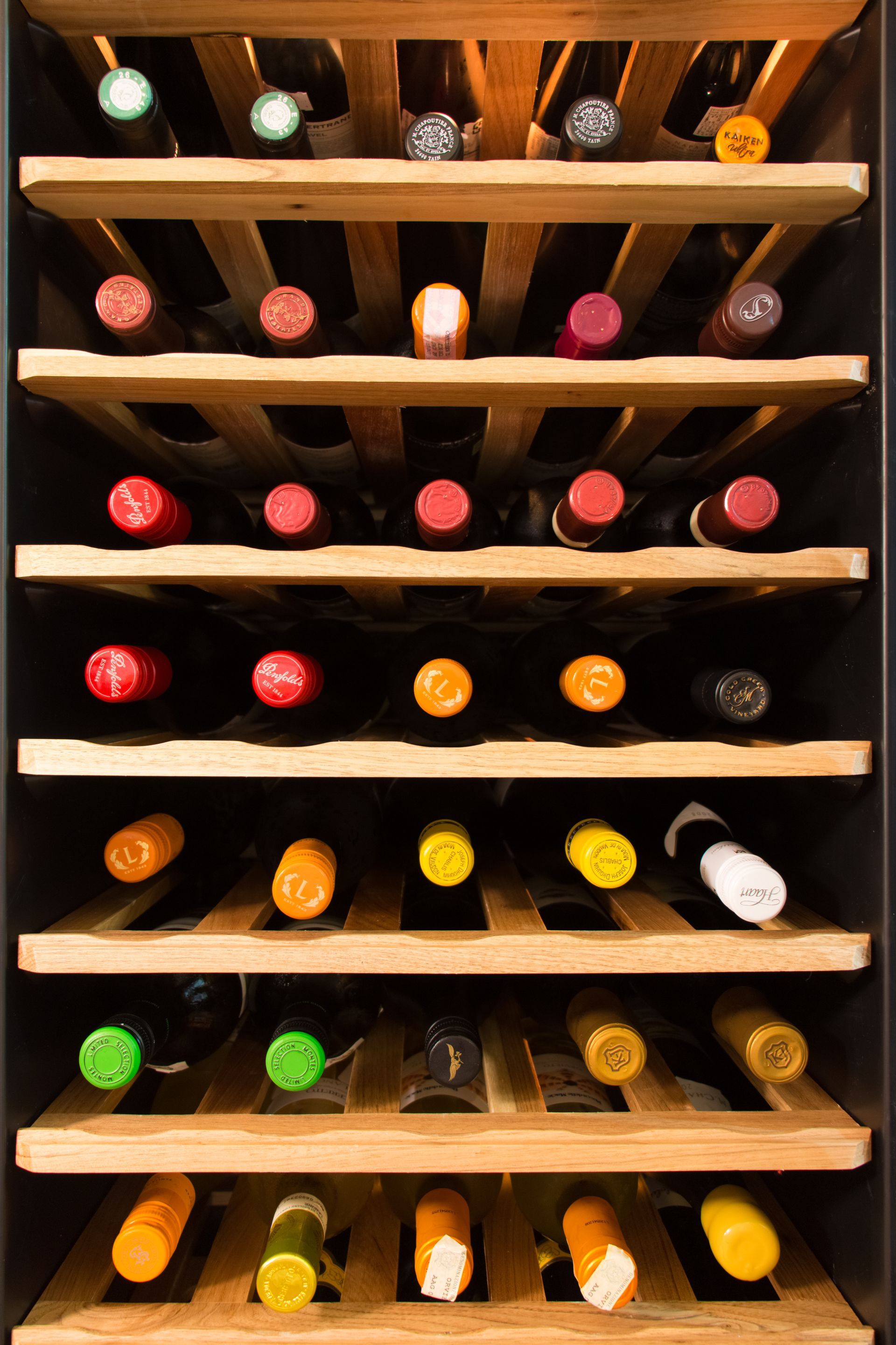 A wine cooler filled with bottles of wine of different colors.