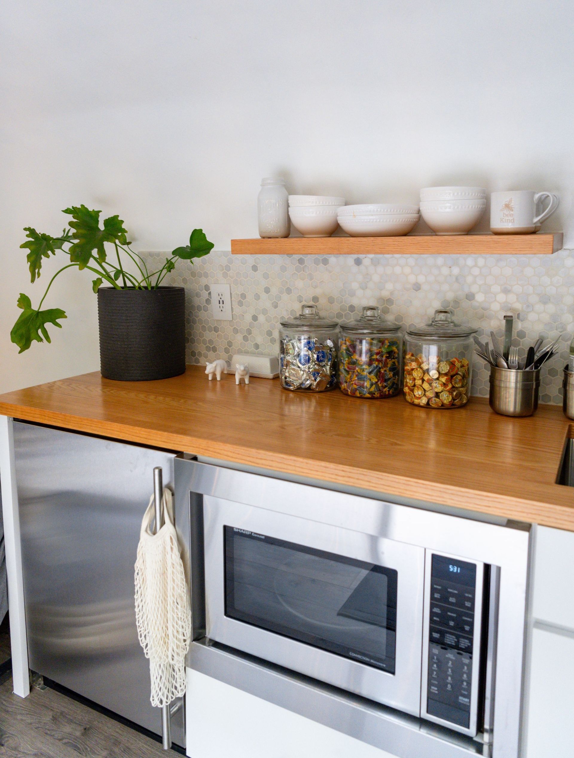 A kitchen with a stainless steel microwave and a wooden counter top