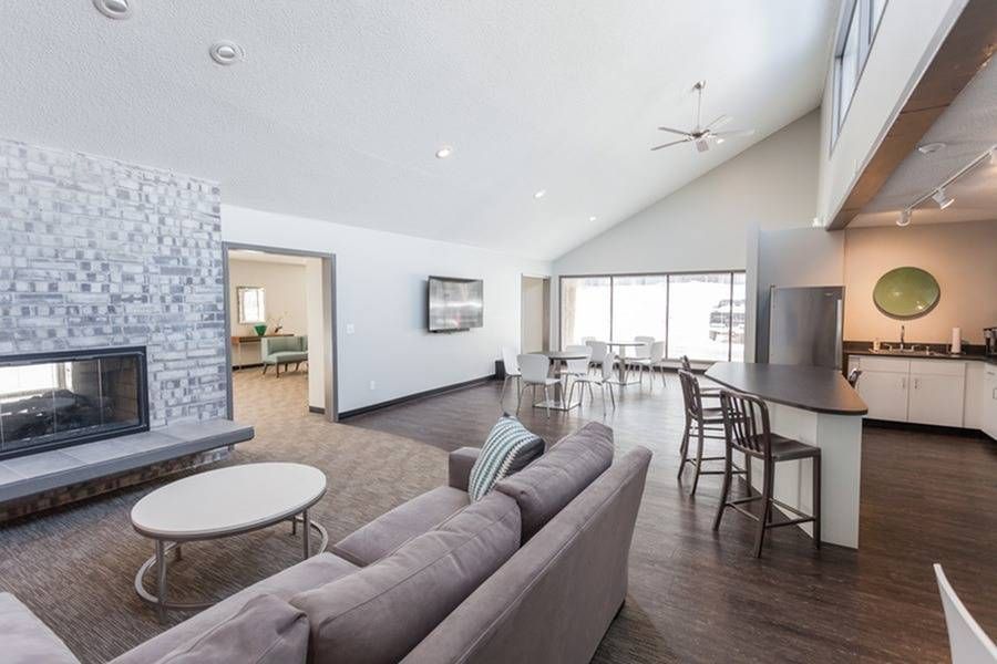 Spacious living room with a fireplace, sofa, bar, and dining area. Neutral colors with modern design.