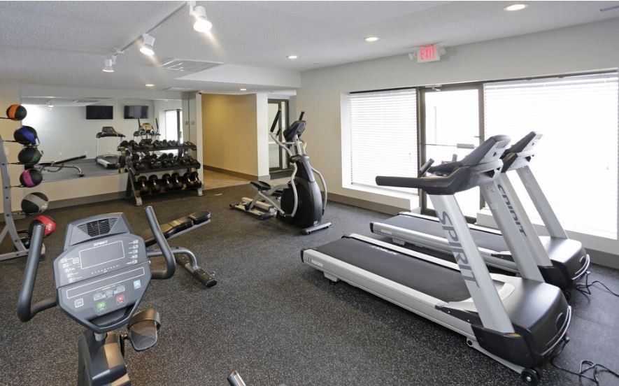 Interior view of a fitness center with treadmills, a stationary bike, weights, and mirrors.