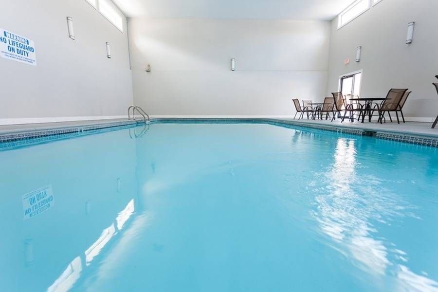 Indoor pool with clear blue water and seating area along the wall.