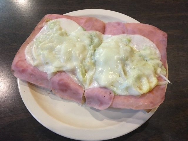 A white plate topped with ham and eggs on a table A white plate topped with ham and eggs on a table