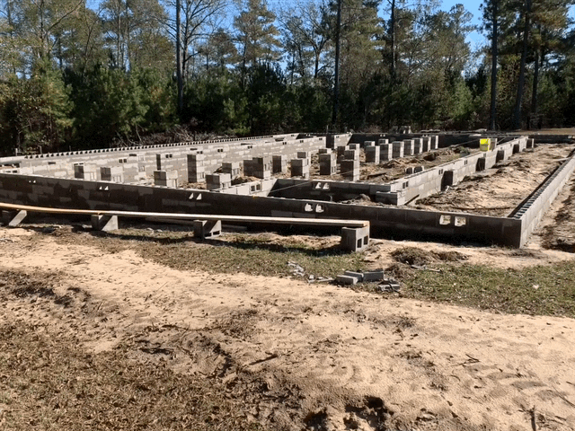 A foundation for a house is being built in the middle of a dirt field.
