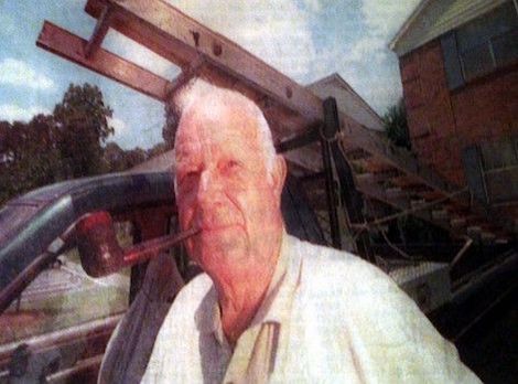 A man is sitting in a car with a ladder in his mouth.