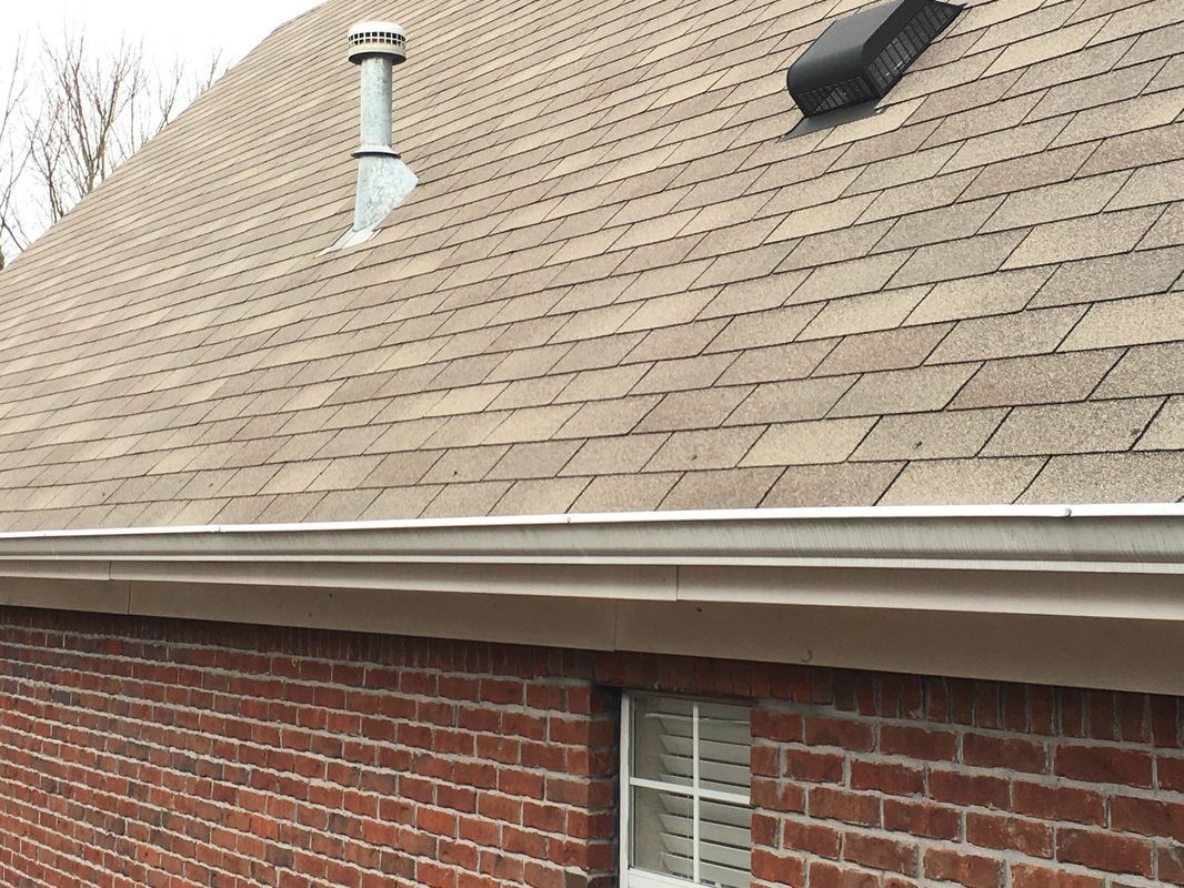 A brick house with a tan roof and a window
